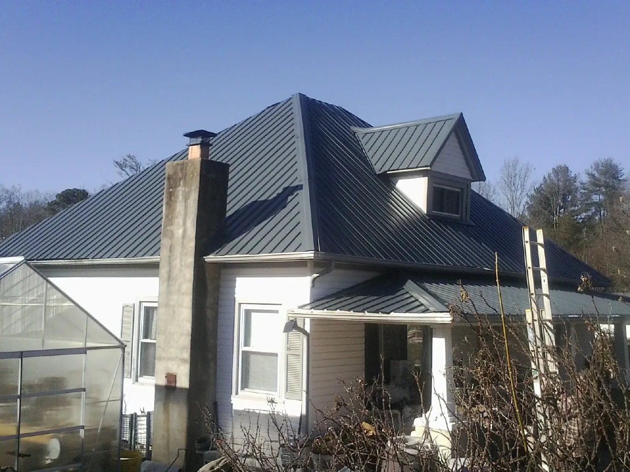 Dark blue standing seam metal roof on a white farmhouse with dormer — Slate & Tile Roof Repair by Roofing Brothers in Anacortes