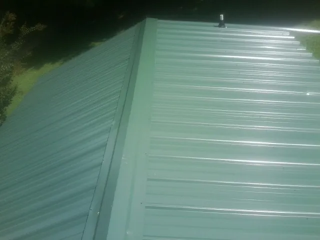New green metal panels meeting at the ridge of a roof — Flat Roof Repair work by our crew in Anacortes