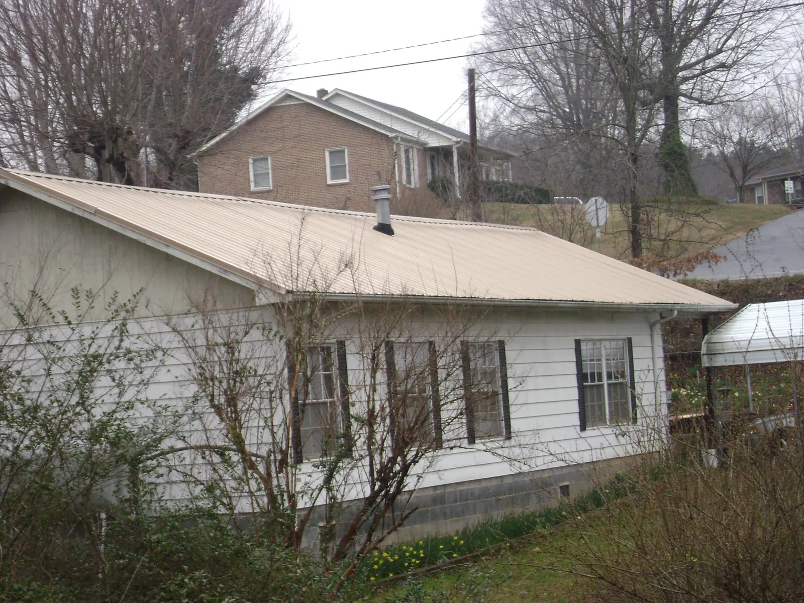 Tan metal roof on a white sided house set into a hillside — Commercial Roofing by Roofing Brothers in Anacortes
