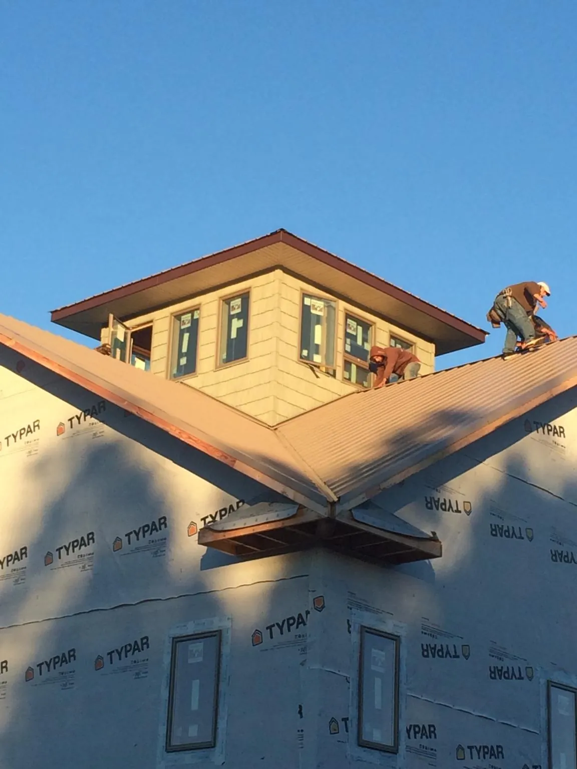 Roofers working around a rooftop cupola on a new metal roof at sunset — Roof Waterproofing in Anacortes by Roofing Brothers